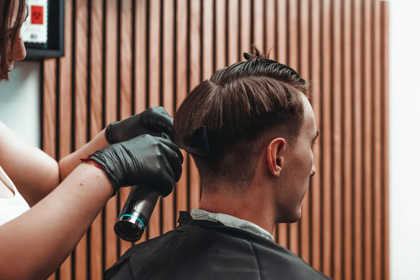 Holič v Medusa Barber upravuje vlasy zákazníka